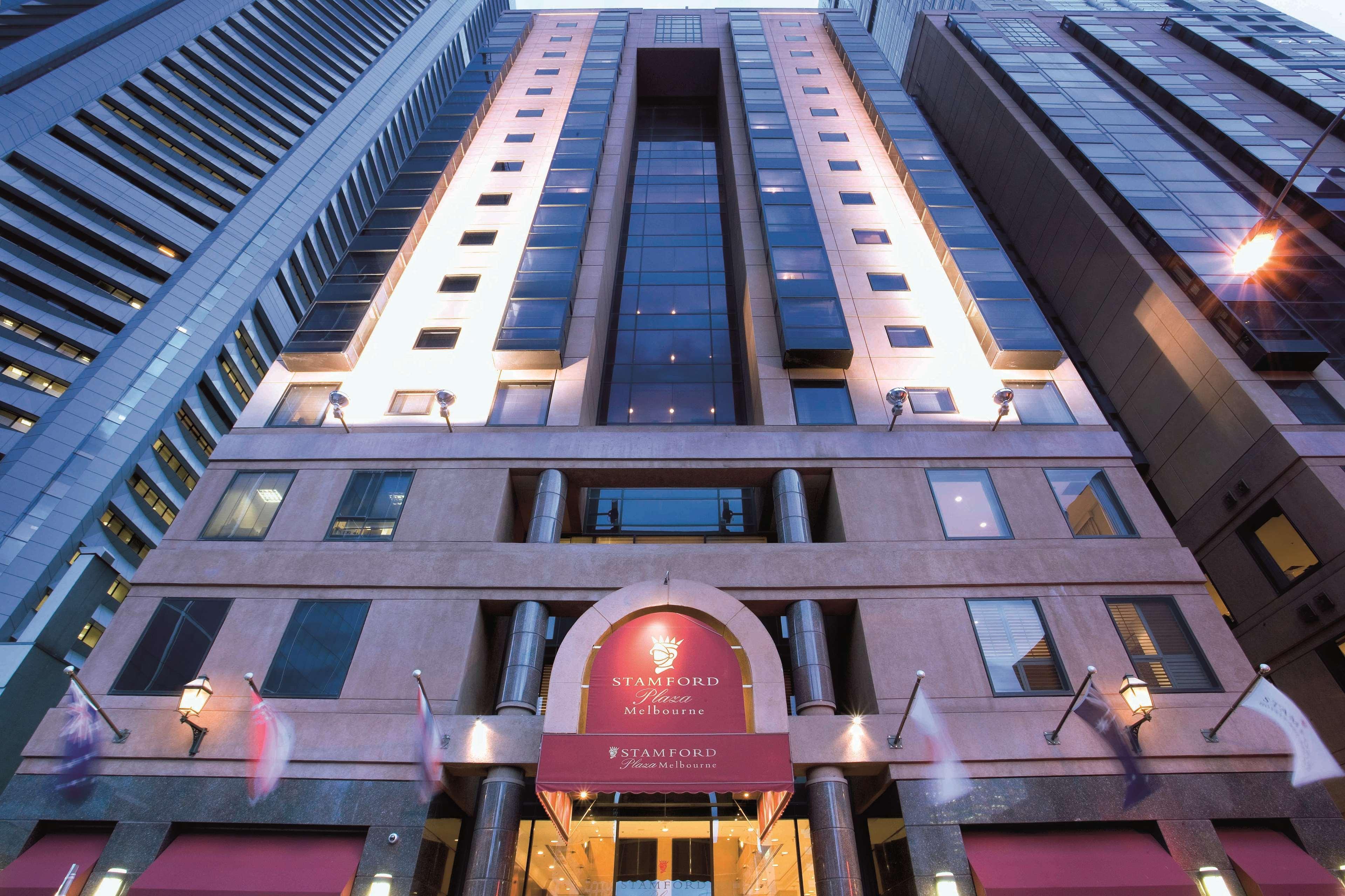 墨尔本斯坦福广场酒店 外观 照片 The photo shows the exterior of a modern hotel building. The structure appears tall and features a combination of glass and stone elements. Large windows are prominent, particularly in the center section, which suggests a contemporary architectural s